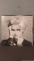 Front cover of Madonna first self-titled record album showing portrait photo of Madonna with styled hair and bracelets on wrist.