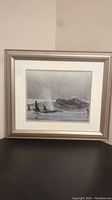 Full view of framed orca whale print hung on wall showing metallic silver frame and double white matting.
