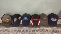 Photo of six hats lined up side by side showing front logos and colors