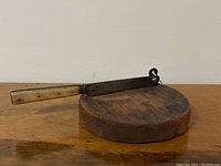 Photo of antique round wooden chopping block with cheese cutter attached, showing side view and handle