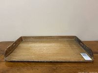 Front angled view of rectangular wooden dough board with raised edges and cutout handles on side panels showing wood wear and patina.