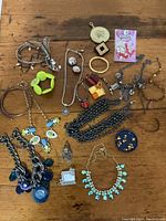 Full lot showing diverse assortment of necklaces, bracelets, earrings, and charms arranged on wooden surface