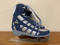 Side view of one navy blue and grey Softec figure skate showing soft boot with lace-up and Velcro strap.