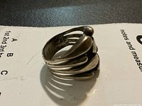 View of the sculptural sterling silver ring showing multi-band teardrop shapes forming the band, slightly tarnished.