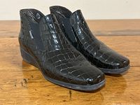 Side angle view of the black patent leather ankle boots with alligator print, showing elastic panel and wedge heel.