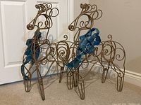 View of two metallic gold wire reindeer sculptures with blue metallic ribbon bows, showing front and partial side angles.