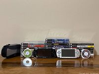 two PSP handheld consoles, carrying case, loose UMD discs and stacked game cases