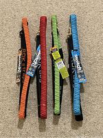 Four ROK Stretch dog leashes in orange, red, green, and blue arranged side by side showing colors and tags.
