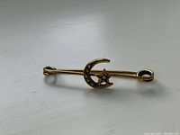 Front view of the Victorian crescent moon and star brooch showing gold and seed pearl details.