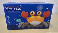 Blue and orange crab toy shown with box packaging labeled 'Electric Induction Cute Crab' indicating light and sound features.