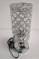 Full front view of the cylindrical crystal lattice decorative lamp on its round chrome base, showing power cord and switch.