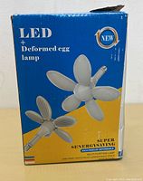 Box showing the lamp's name 'LED + Deformed egg lamp' and an illustration of the flower-shaped light with multiple panel petals.