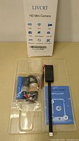 LIVCRT HD Mini Camera with USB cable, blue accessory, and quick start guide in clear plastic packaging.