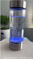 Hydrogen water bottle filled with water, blue LED light activated, visible bubbles inside indicating hydrogen infusion process.