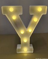 Front view of the LED letter Y lit up, showing warm white glowing bulbs embedded on white plastic base and letter.