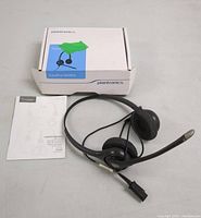 Plantronics SupraPlus HW261N binaural noise cancelling headset laid out with attached cable and microphone, next to original box and user manual.