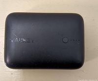 Top view of the black Aukey power bank showing logo, power button and LED charge indicator lights.