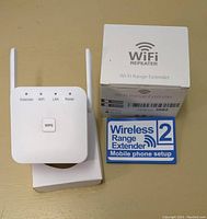 Photo showing the Wi-Fi repeater alongside its original box and a setup instruction card.