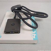 WARRKY 4K HDMI dual input video switch adapter with two HDMI ports, a button on top, and a braided output cable.