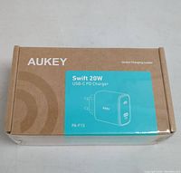 Photo of Aukey Swift 20W USB-C PD Charger box, showing product name and model PA-F1S on turquoise label on brown cardboard box.