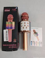 Wireless microphone in rose gold with white speaker control panel and colorful LED lights, next to original box and microphone manual.
