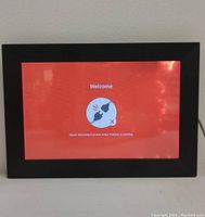 Front view of the digital photo frame displaying a welcome screen with instructions.