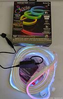 Unboxed flexible LED neon strip light laid out with power adapter and controller visible, illuminated showing color flow