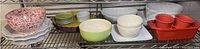 Shelf showing multiple ceramic and porcelain items including bowls, plates, and baking dishes in various colors and styles