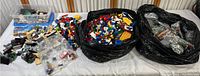 Wide view of collection showing multiple bags and containers full of assorted LEGO pieces and bricks.