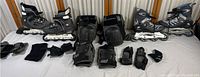 Two pairs of Solomon rollerblades size 8 and 9 with various black and grey protective pads and gloves included, laid out on a white surface.