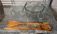 Two vintage Anchor Hocking glass pitchers and two olivewood salad serving spoons on bubble wrap.