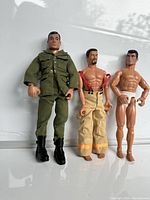 Three action figures: soldier in uniform, firefighter bare-chested with pants and suspenders, muscular man in briefs