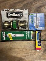 Photo of Kwikset door knob in packaging and three different types of light bulbs including Sylvania compact fluorescent and aquarium light bulb
