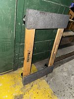 Front view of the Milwaukee dolly showing brand name and carpet padding on the upper and lower horizontal frame pieces.