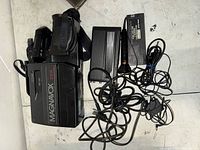 Top view of Magnavox VHS HQ CCD camcorder with attached battery pack, charger, and power cables spread around.
