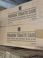 Two unopened cardboard boxes labeled 'Premium Tomato Cage' with plant stakes and support clips, each box contains set of 3, 5.5 feet tall