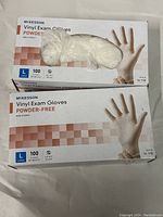 Two boxes of McKesson large vinyl exam gloves, powder-free, one box open with gloves visible inside, the other closed.