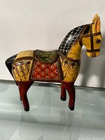 Photo showing the left side of the hand painted wooden horse with detailed patterns on the body and saddle.