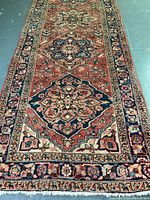 Full length view of Heriz wool runner rug showing rust red base and cream and navy blue patterned borders with central geometric medallions.