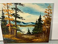 Front view of the oil painting showing the landscape scenery with trees, lake, and mountains.