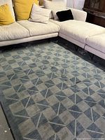 Full view under light-colored sectional sofa showing entire rug layout and pattern