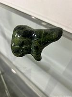 Side angle photo of the green stone bear figurine showing smooth polished surface and shape details.