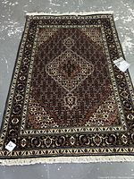 Full view of rug laid flat on concrete floor showing overall pattern and fringe.