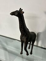Front side view of the dark wooden giraffe figurine showing detailed textured spot carving and shape