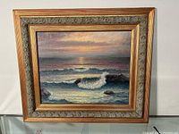 Frontal view of the oil on board seascape painting in ornate gold-toned frame, showing full composition of waves crashing under a sunset sky.