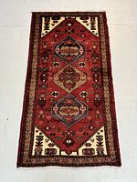 Full view of rectangular red wool rug with central medallions and borders