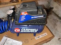Overview photo of Campbell Hausfeld air compressor unit with blue tank and hoses