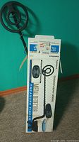 Photo of the Discovery 3000 metal detector on box showing the full unit including circular search coil, telescopic shaft, and battery box.