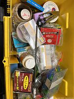 Yellow toolbox with assorted nails, screws, staples, anchors, and hardware items in plastic containers and boxes