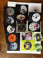 Photo showing Xbox 360 and PS3 game discs in cases, Wii active game disc, multiple game discs visible with various titles